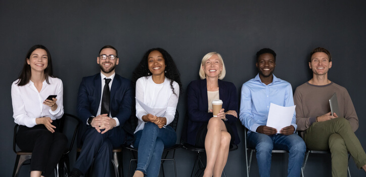 Diverse successful staff seated on chairs smiling looking at camera