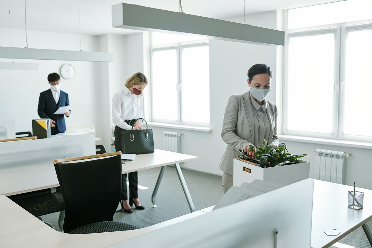 Young office workers in formalwear and protective masks standing by their desks Staff returning to the work desks during office reopening