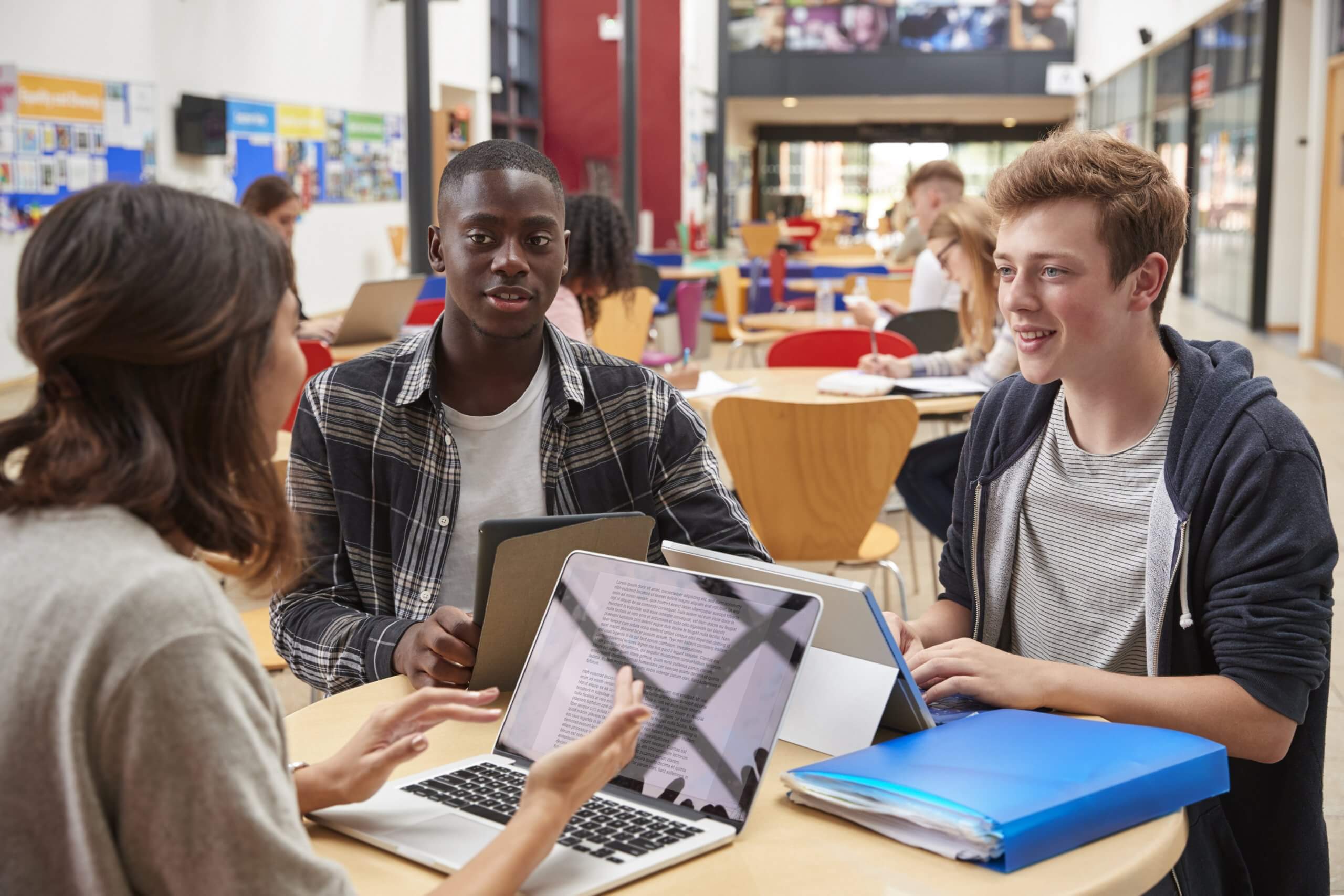 Teacher Talks To Students In Communal Area of College Campus