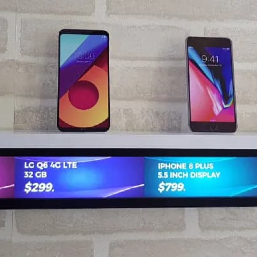 Smartphones lined up on retail shelf with IAdea digital shelf-edge advertising screens