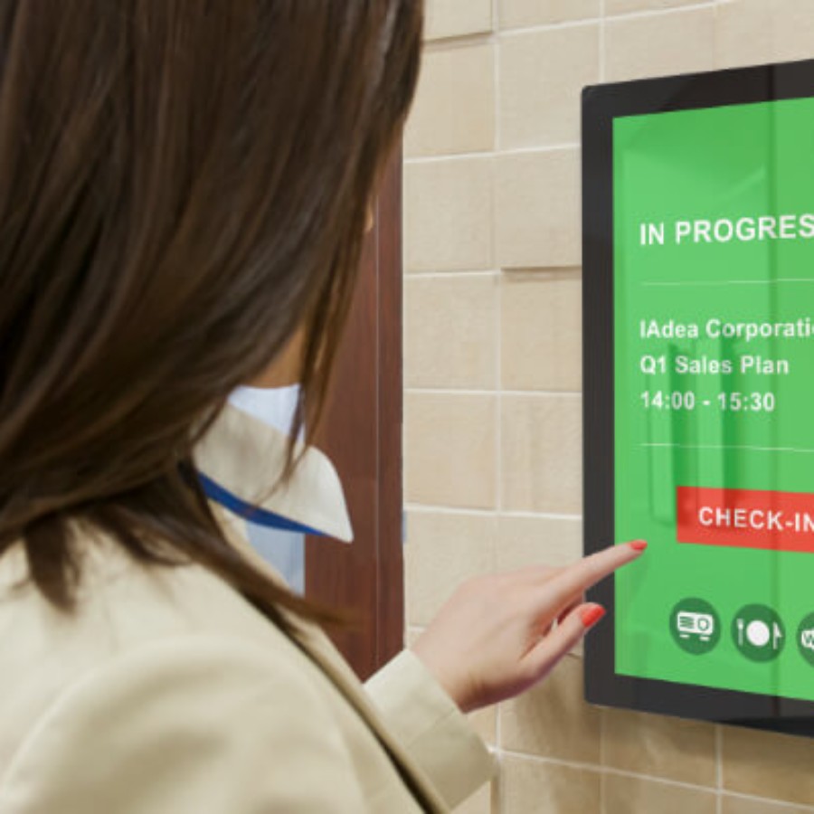 Person interacting with a touchscreen display kiosk in an office lobby for IAdea wayfinding